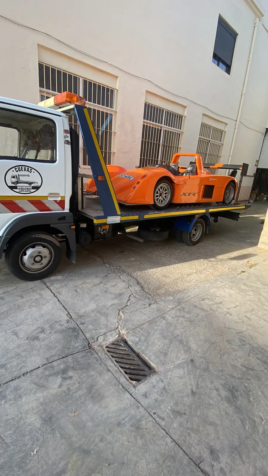 Prototipo naranja de competición sobre grúa